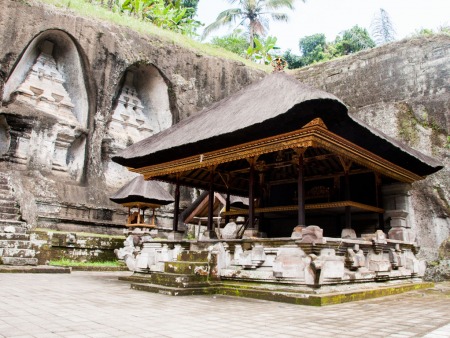 Under covered temple with rock-cut candi (shrines) in background
