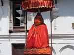 Hanuman statue cloaked in red and sheltered by an umbrella