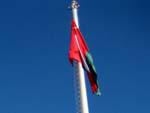 Omani flag at the central tower with the mosque's minaret in the background