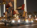 Many men standing on their cars holding Qatar flags