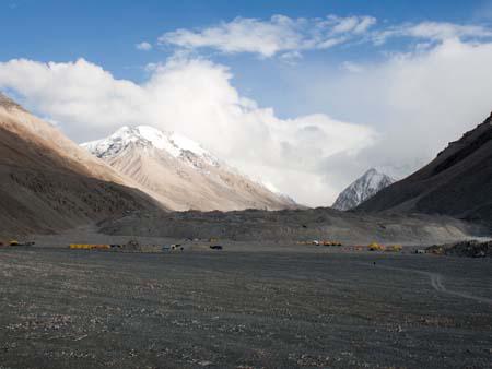 View of cloud covered Everest from Base Camp, yellow tents belong to the climbers
